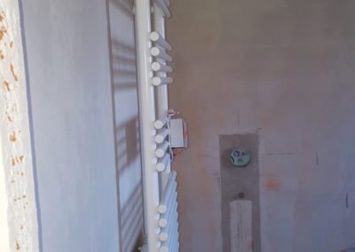 Sèche serviette blanc sur un mur nu dans une pièce en travaux