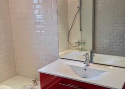Meuble de salle de bain rouge avec vasque blanche dessus et douche/baignoire à gauche Manu Casier Thonon