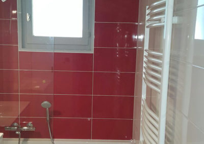 Douche/baignoire avec carrelage rouge et paroi transparent. Sèche serviette blanc Manu Casier Thonon